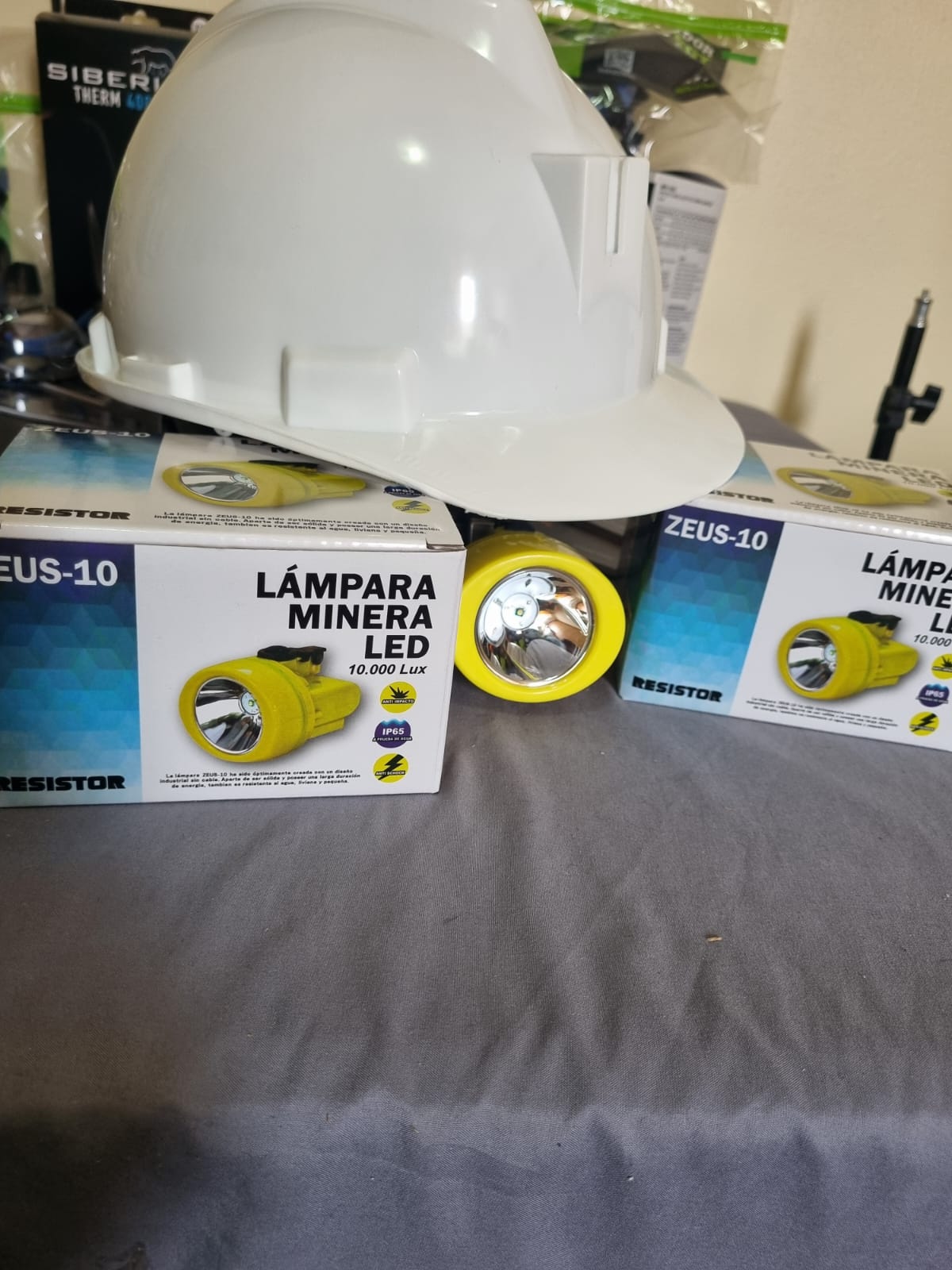 Presentación comercial de lámpara minera ZEUS 10 con accesorios y entorno industrial